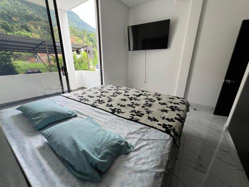 a bedroom with a bed with a tv on the wall at Imperial Emerald House in Muzo