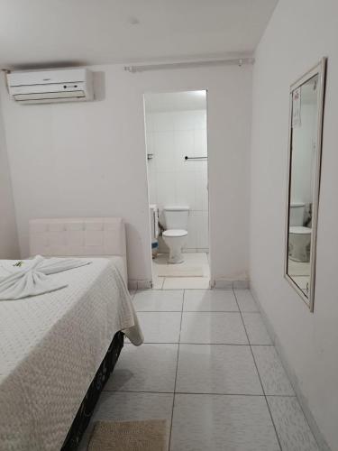 a bedroom with a bed and a bathroom with a toilet at Hospedaria Temporarte in Piranhas