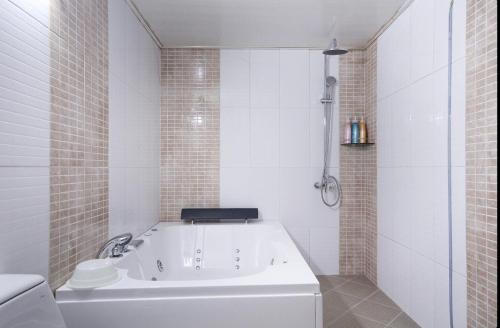 a white bath tub in a bathroom with white tiles at Dongdaegu Leaders Hotel in Daegu