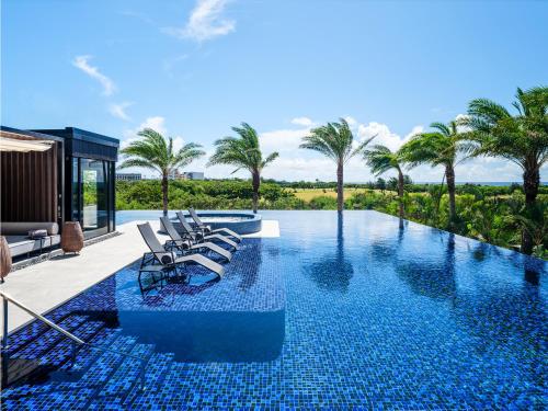 a swimming pool with lounge chairs and palm trees at seven x seven ISHIGAKI in Ishigaki Island