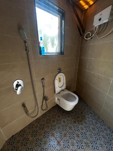 ein kleines Badezimmer mit Toilette und Fenster in der Unterkunft NESTORY forest retreat in Kolvan