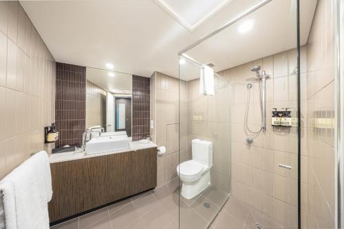 a bathroom with a toilet and a sink and a shower at Hotel Grand Chancellor Townsville in Townsville