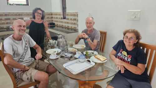 a group of people sitting around a table with food at lakeview homestay in Trikarpur