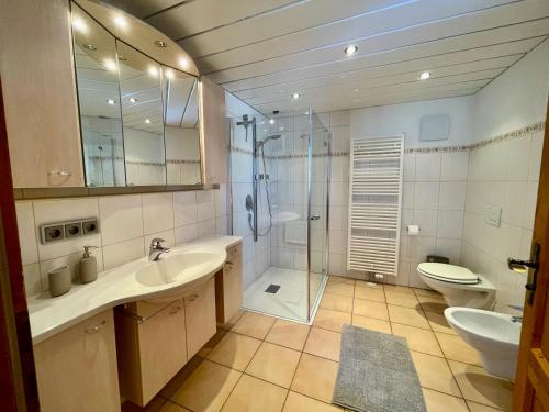 a bathroom with two sinks and a shower and a toilet at Ferienhaus Alpenherz Sommer-Bergbahnen-kostenlos in Bolsterlang
