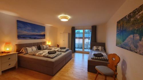 a bedroom with two beds and a chair and a window at Ferienhaus Alpenherz Sommer-Bergbahnen-kostenlos in Bolsterlang