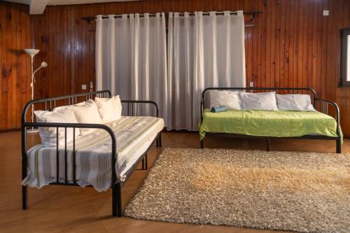 a room with two beds and a rug and a window at Abrigo dos Prazeres Guesthouse by Mth in Prazeres