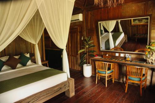 a bedroom with a bed and a desk with a mirror at Ardan Maison The Garden Villas in Ubud