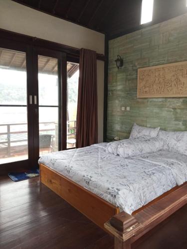 a bedroom with a bed and a large window at Homestay Mroom Bali in Perean