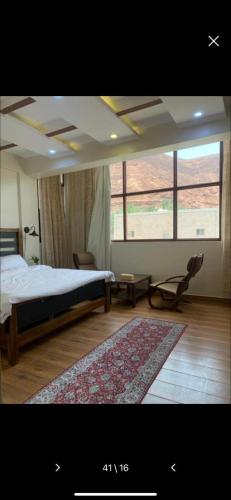 a bedroom with a bed and a chair and a rug at Mabiti hotel in Al-ʿUla