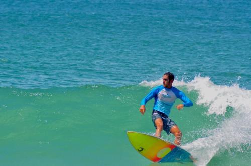 a man riding a wave on a surfboard in the ocean at Leal Surf School in Rio de Janeiro