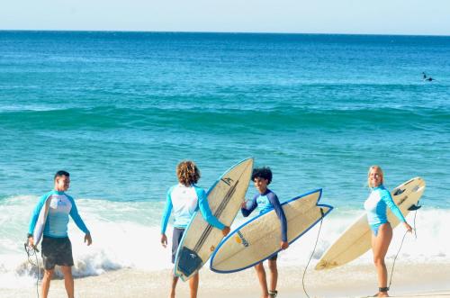 a group of people standing on the beach with surfboards at Leal Surf School in Rio de Janeiro