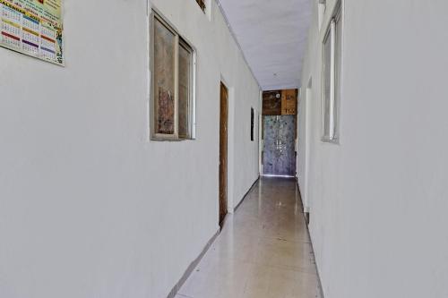 a hallway with white walls and white floors and windows at SPOT ON HOTEL MOONLIGHT in Bhilai