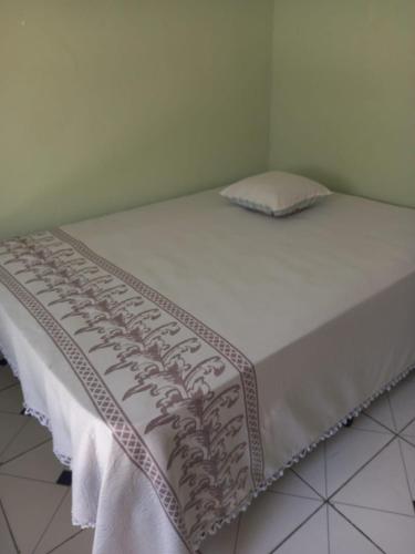 a bed with a white sheet and a pillow on it at Lar da Dona Judite in Pontal do Paraná