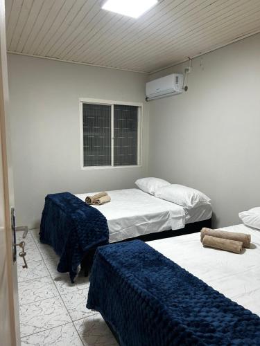 a room with three beds with blue and white sheets at Pousada Pampeano in São Gabriel