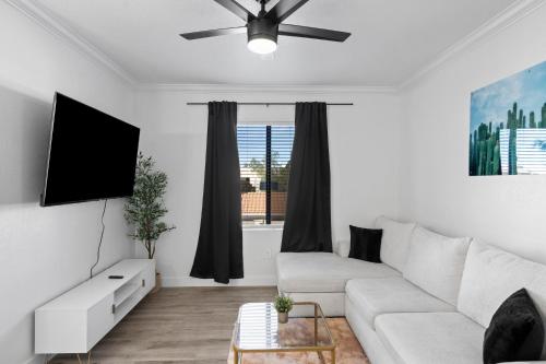 a living room with a white couch and a flat screen tv at Resort-Style 3RB-2BR-1BR Retreat, Pool, Gym, Parking in Tempe