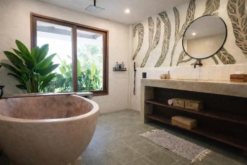 a bathroom with a large tub and a mirror at Sleepy Gypsea Villa Siargao in Siargao Island