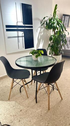 a glass table with two chairs and a potted plant at Cabrero Beach 1212 in Cartagena de Indias
