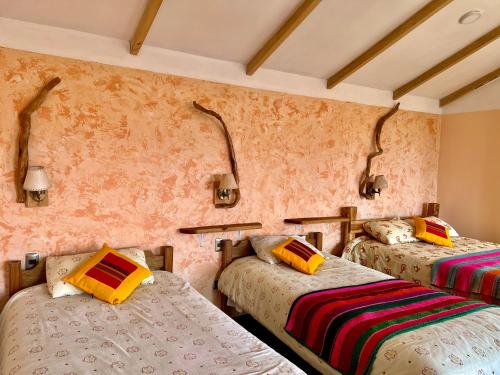 two beds in a room with pink walls at Inkapacha ecohostel cabañas in Comunidad Yumani