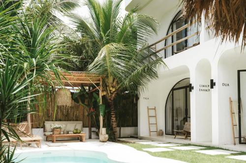 a courtyard with a palm tree and a pool at Tyde Bali Boutique Hotel in Uluwatu