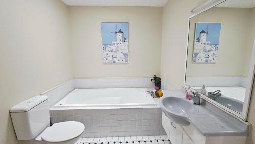 a bathroom with a tub and a toilet and a sink at Lilypad of Three Kings - Family friendly w Kitchen & Parking in Auckland