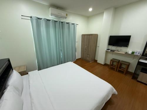 a bedroom with a large white bed and a television at The Burapa Rooms in Bangkok