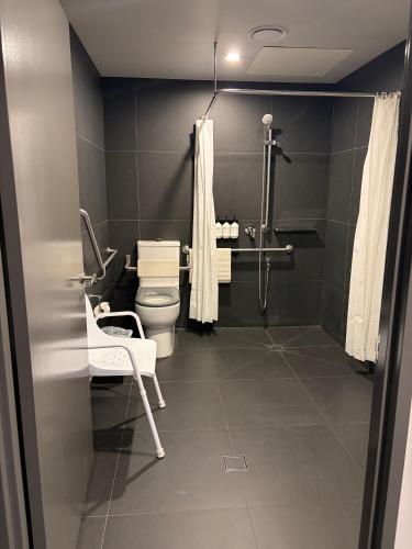 a bathroom with a toilet and a chair in it at Abode Belconnen in Canberra