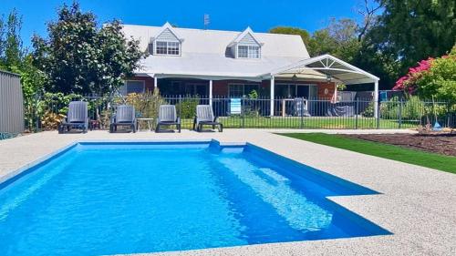 a swimming pool with two chairs and a house at Sandy Feet Retreat in Geographe