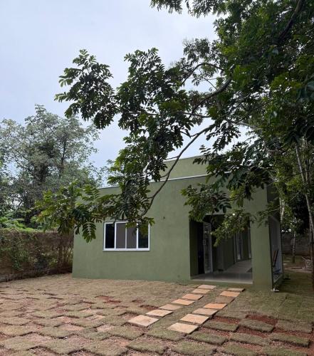 a green house with a brick driveway in front of it at Casa 3 Suites Confortaveis in Chapada dos Guimarães