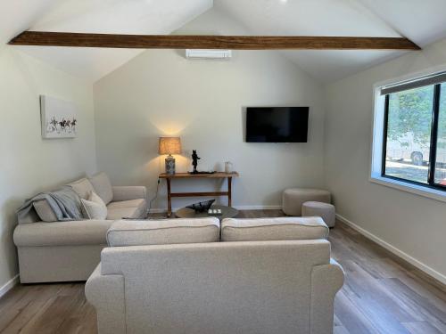 a living room with two couches and a tv at The Grain Shed in Euroa