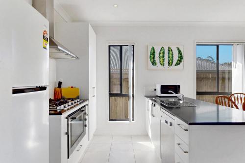 a kitchen with white cabinets and a counter top at 4BR Family Home Coomera Theme Parks Shopping in Gold Coast