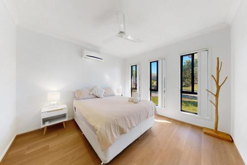 a white bedroom with a bed and some windows at 4BR Family Home Coomera Theme Parks Shopping in Gold Coast