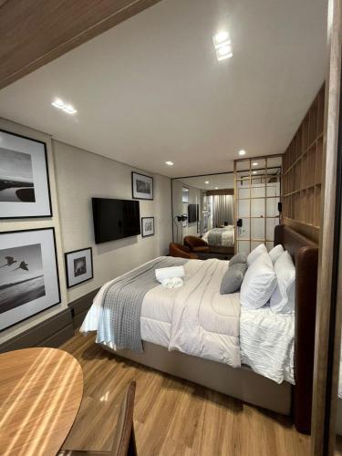 a bedroom with a large bed and a television at Loft de Luxo com Charme e Design Moderno in Cuiabá