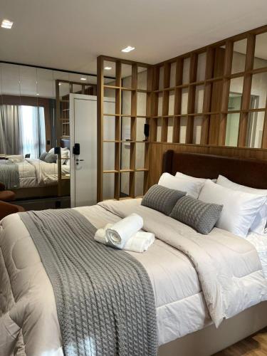 a bedroom with a large bed with two towels on it at Loft de Luxo com Charme e Design Moderno in Cuiabá