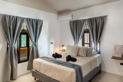 a bedroom with a bed and two windows at KAIA VILLAGE, Santa Teresa, Costa Rica in Santa Teresa Beach