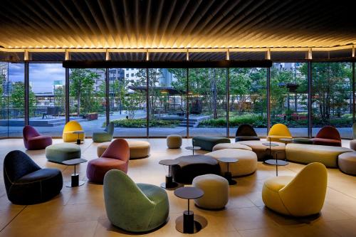 a lobby with colorful chairs and tables and windows at OMO7 Osaka by Hoshino Resorts in Osaka