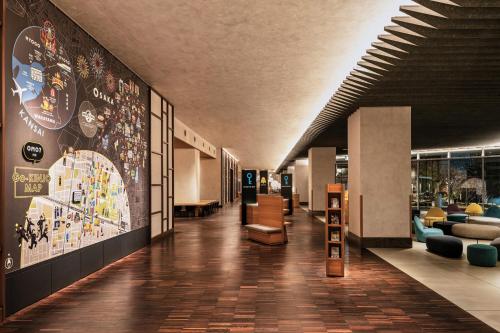 a hallway with a lobby with couches and paintings on the walls at OMO7 Osaka by Hoshino Resorts in Osaka
