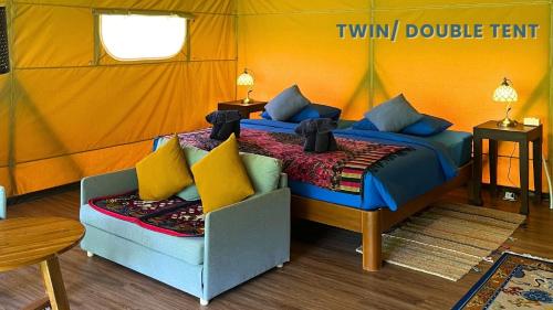 a bedroom with two beds and a couch in a tent at THANYAWANA Glamping Tents in Khao Sok National Park