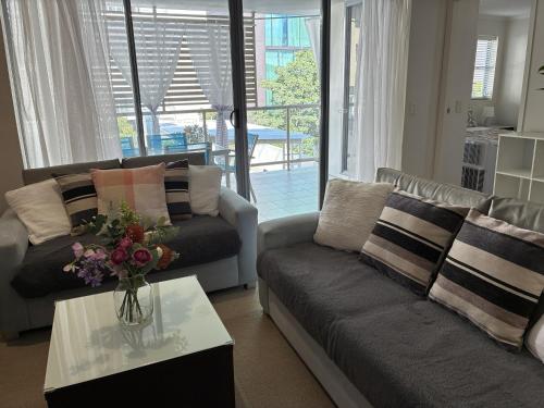 a living room with a couch and a vase of flowers on a table at Merivale stay in South Brisbane two beds two baths one parking in Brisbane