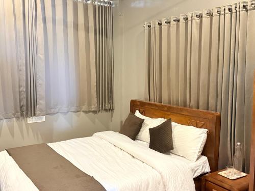a bedroom with a bed with white sheets and pillows at Valensa lake view in Kalpetta