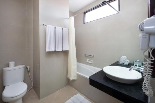 a white bathroom with a sink and a toilet at Adi Dharma Hotel Kuta in Kuta