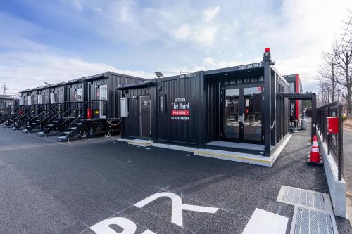 a row of black shipping containers in a parking lot at HOTEL R9 The Yard Ryugasaki in Shōjiki