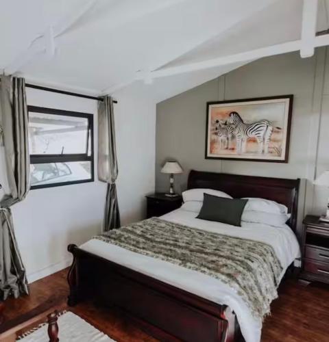 a bedroom with a bed and a picture of a zebra at Chilli cottage - off grid get away in Mkondeni