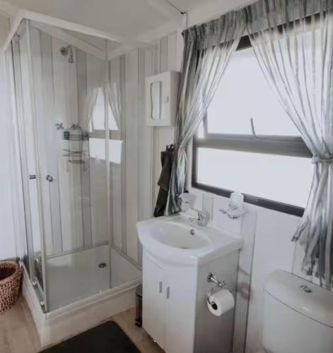 a bathroom with a sink and a shower and a toilet at Chilli cottage - off grid get away in Mkondeni