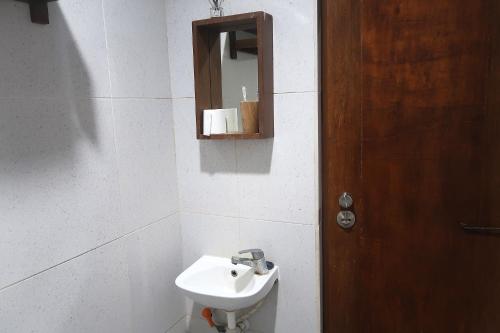 a bathroom with a sink and a mirror and a door at Dermaga Resort Pramuka in Pulau Pramuka