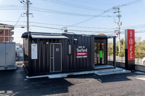 a bus stop with a black building at HOTEL R9 The Yard Tachiarai in Tachiarai