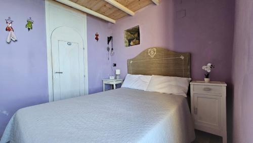 a bedroom with a white bed and purple walls at Agave di mare in Riomaggiore
