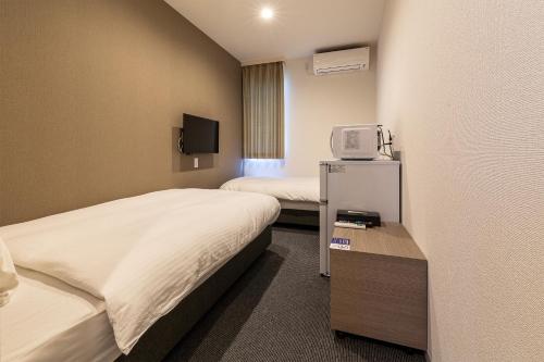 a hotel room with two beds and a tv at HOTEL R9 The Yard Tachiarai in Tachiarai