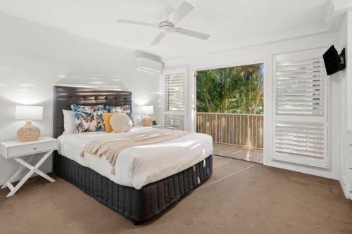 a white bedroom with a bed and a window at Sunset Cove Noosa in Noosaville