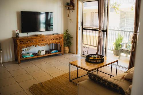 a living room with a television and a table at Surf Shack in Iconic Rainbow Bay - Coolangatta QLD (pet friendly) in Gold Coast