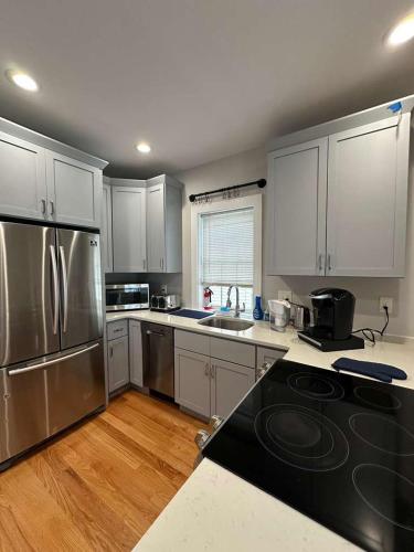 a kitchen with white cabinets and stainless steel appliances at HomeStay in Boston West Bellflower Street in Boston